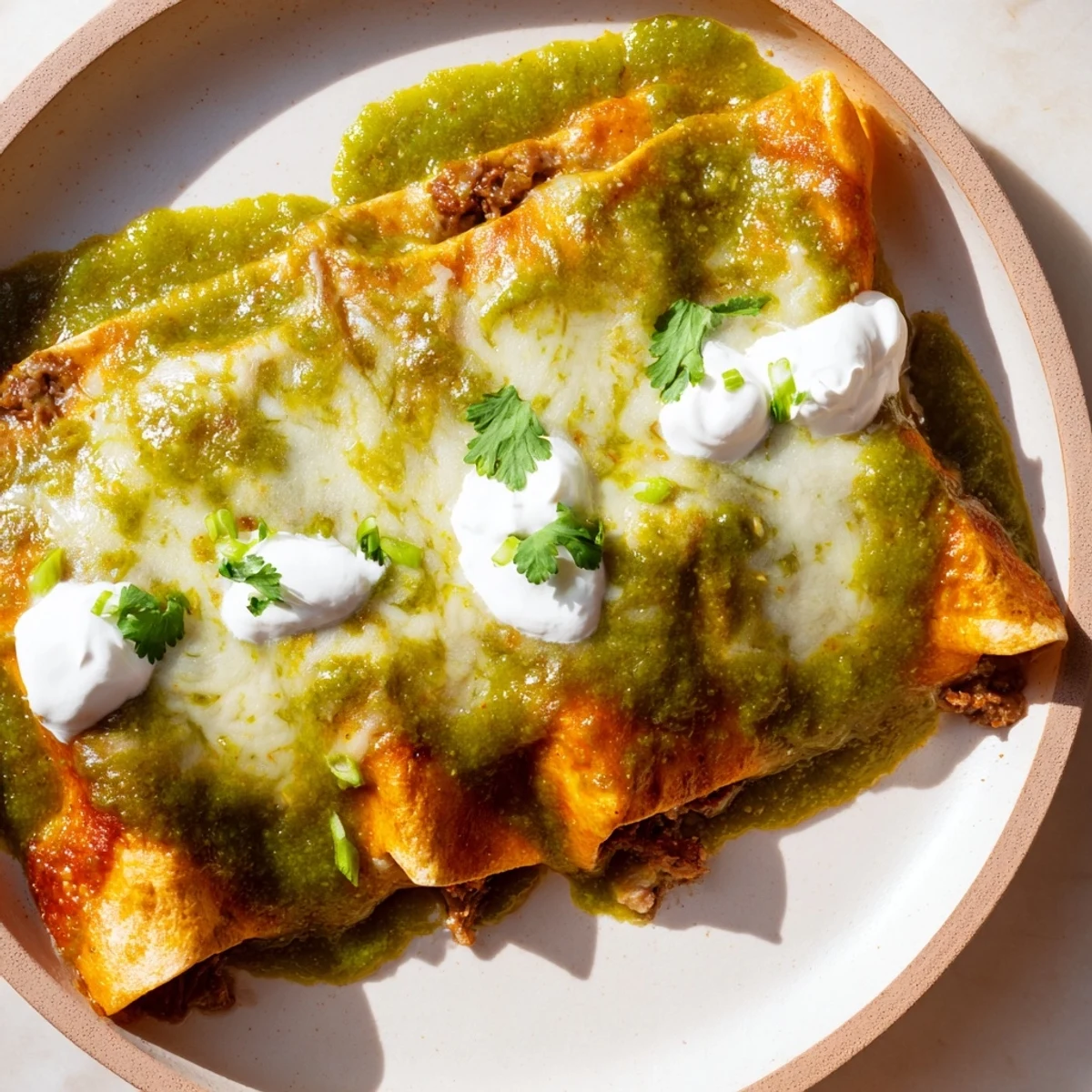 Tender shredded beef fills soft corn tortillas, smothered in homemade green sauce and Monterey Jack cheese.