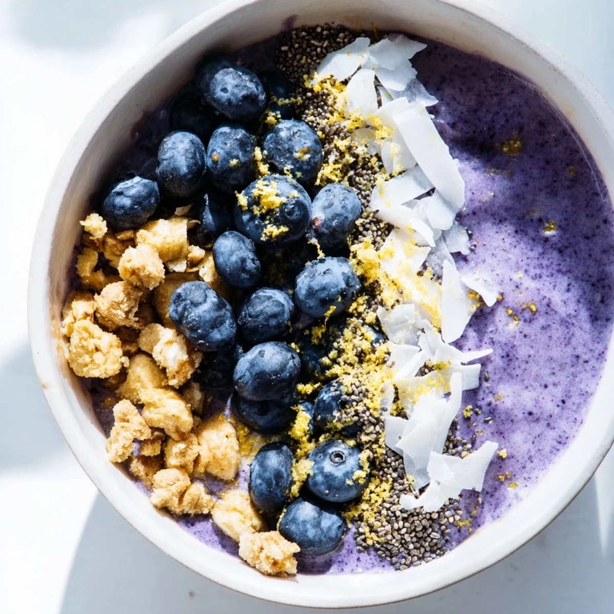 Two bowls of vibrant Lemon Blueberry Smoothie Bowl topped with fresh berries, granola, and coconut flakes for a nutritious breakfast.