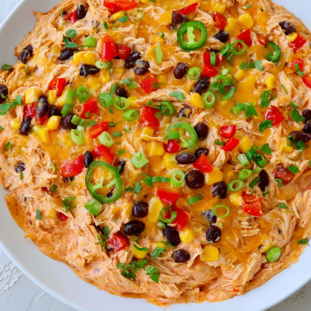 Golden, bubbly melted cheese tops a warm Chicken Enchilada Dip in a baking dish.