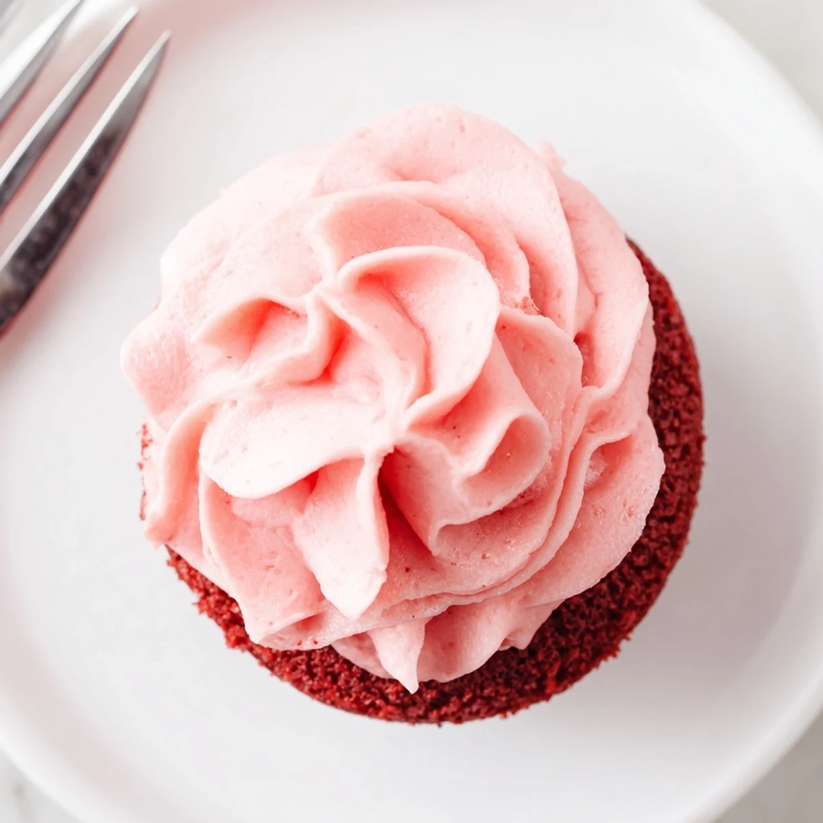 A close-up of a red velvet cupcake with rich pink cream cheese frosting and edible glitter, perfect for a birthday party.  