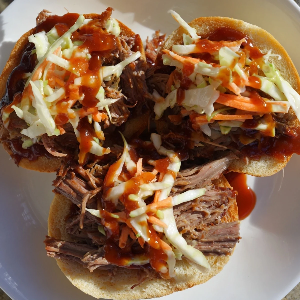 Golden toasted buns filled with smoky BBQ pulled beef, coleslaw, and pickles, served on a platter. 