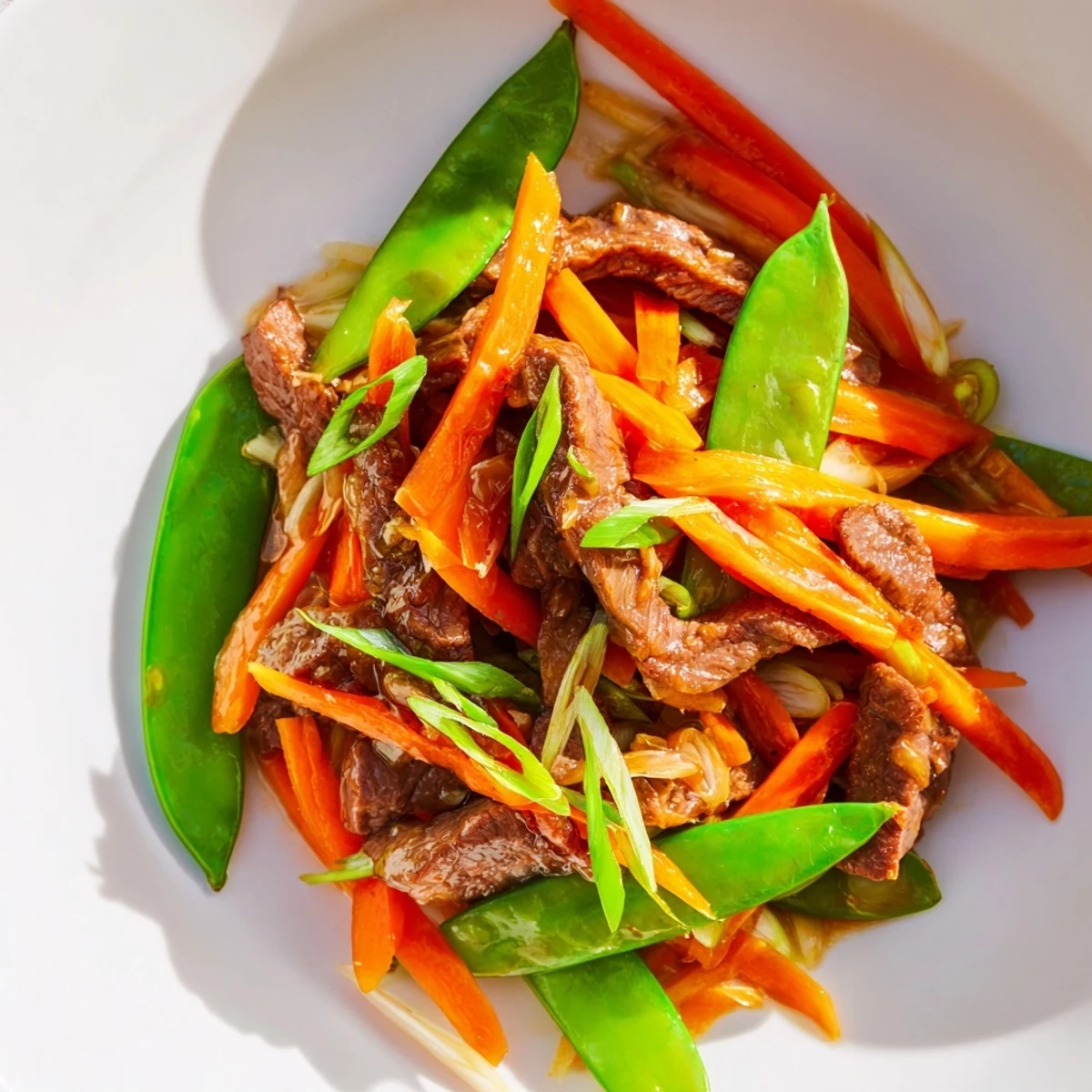 Tender beef strips stir-fried with crisp snow peas and bright carrots in a glossy savory sauce.