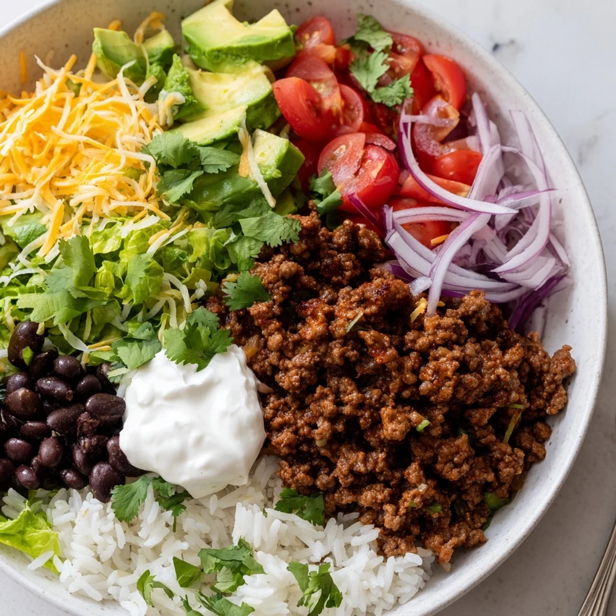 Hearty Beef Burrito Bowls with Rice and Beans served with lime wedges, cherry tomatoes, and shredded lettuce on a rustic table.