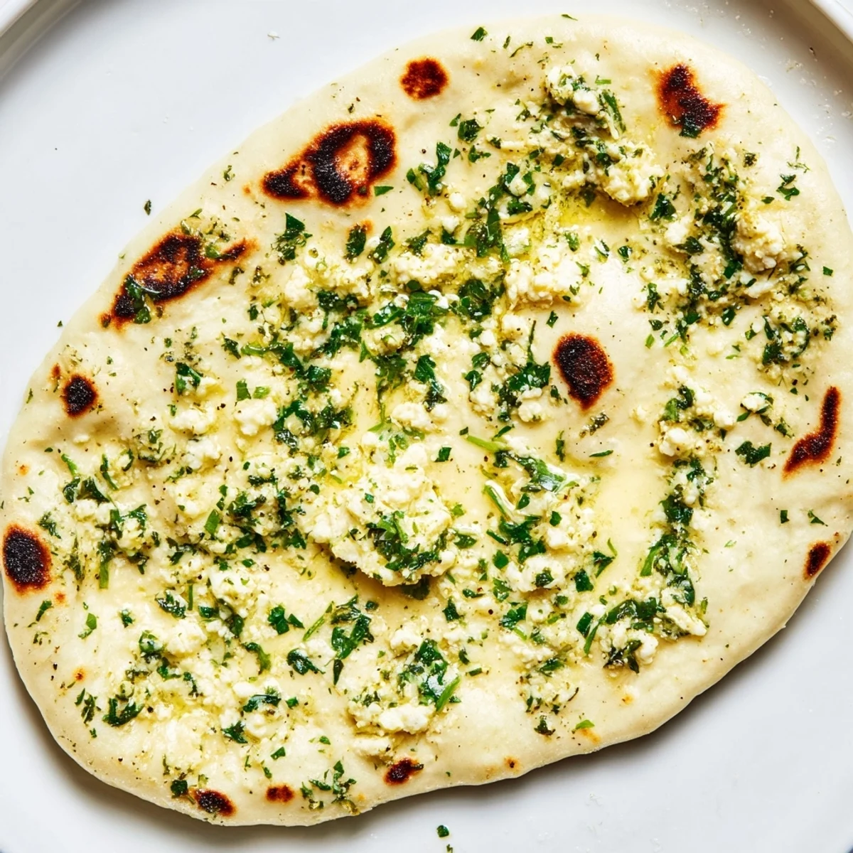 Freshly cooked Cottage Cheese Garlic Naan topped with melted butter and minced garlic, served warm alongside a colorful curry.