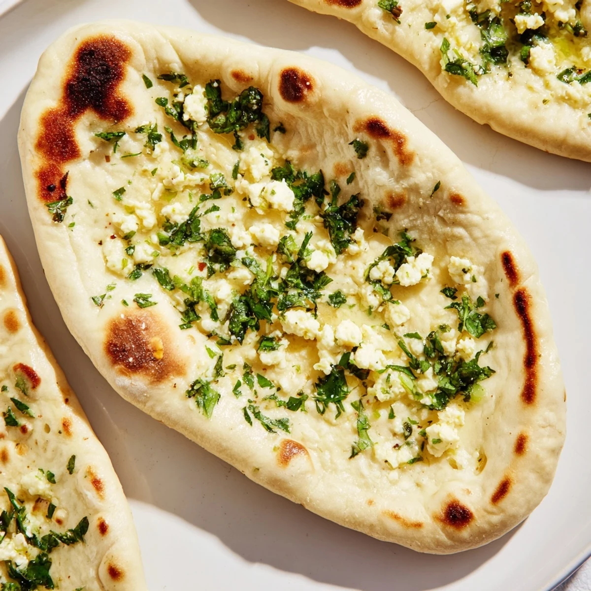 A close-up of Cottage Cheese Garlic Naan stuffed with creamy cottage cheese, garnished with fresh cilantro and sliced green chilies.