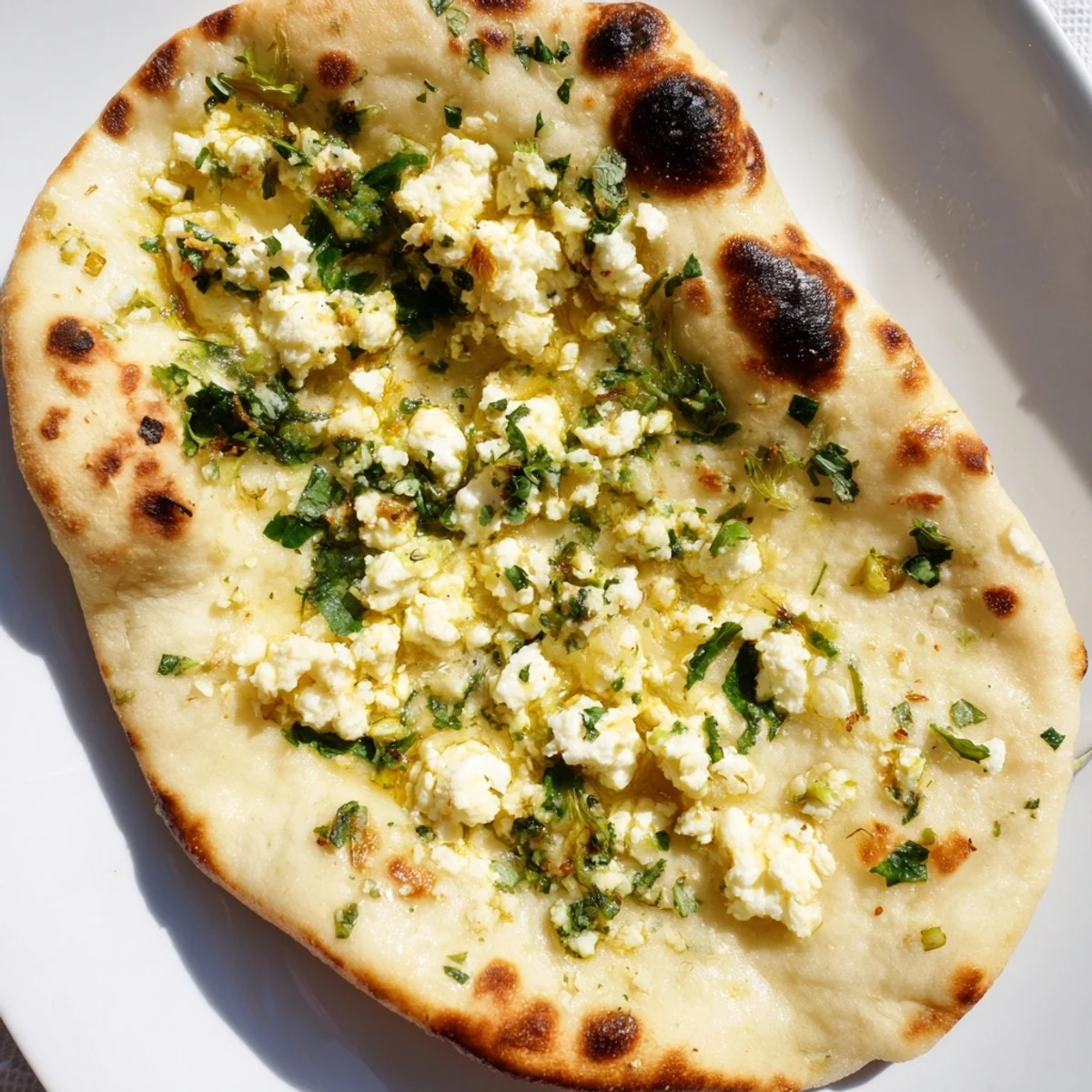 Golden-brown Cottage Cheese Garlic Naan with visible buttery sheen and herbs, perfect for pairing with creamy lentil dal.