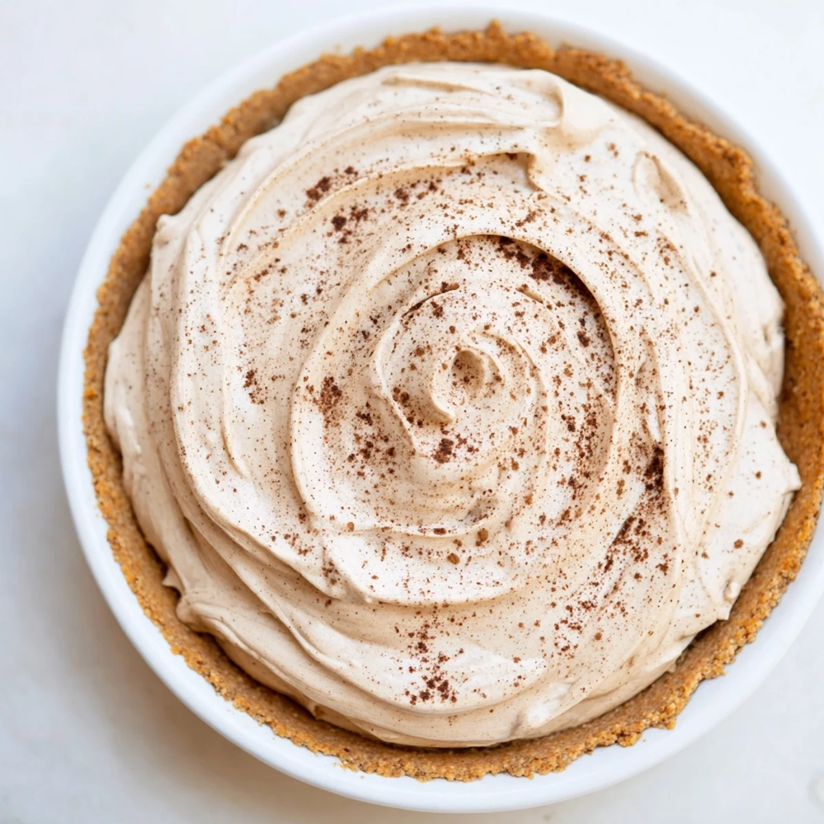 A slice of Keto Cold Brew Coffee Pie on a white plate with a fork, showcasing the creamy filling and almond flour crust.