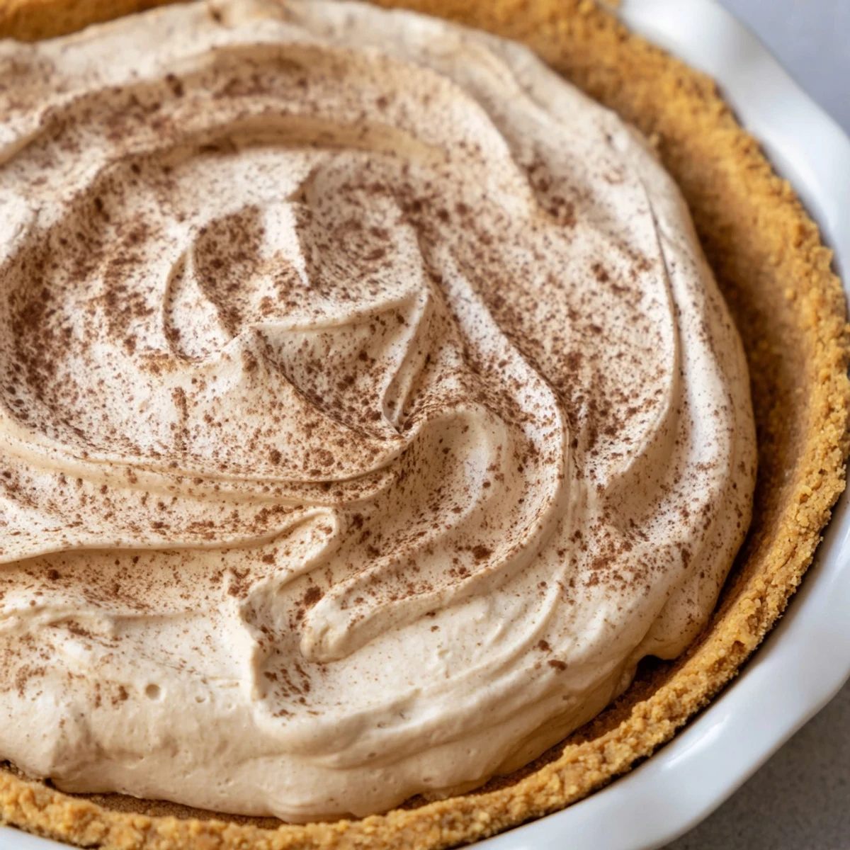 The Keto Cold Brew Coffee Pie garnished with coffee beans sits beside a steaming mug, perfect for a keto-friendly dessert.