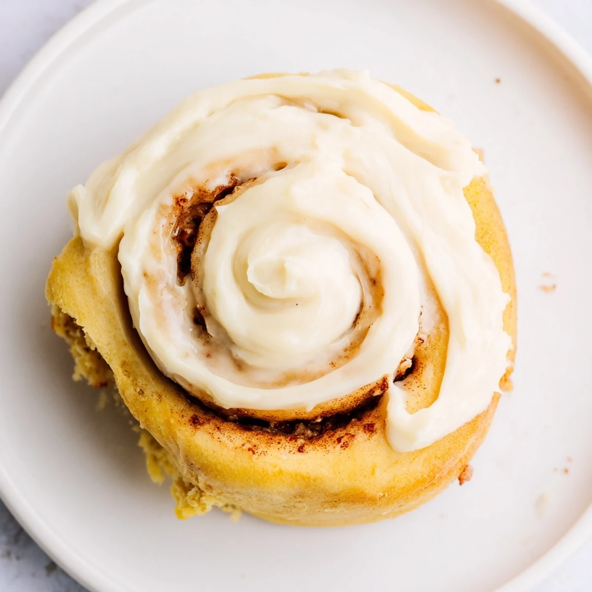 Freshly baked Keto Cinnamon Buns stacked on a white plate, showing fluffy texture inside.