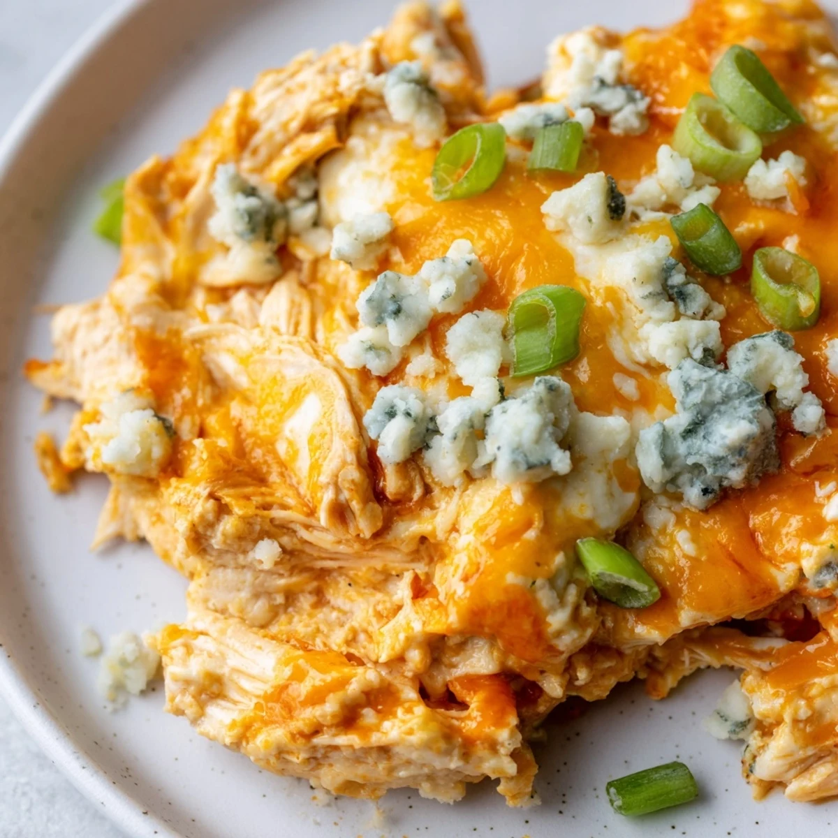 The creamy, spicy dip is served warm with celery sticks and cucumber slices for dipping on a rustic table. 