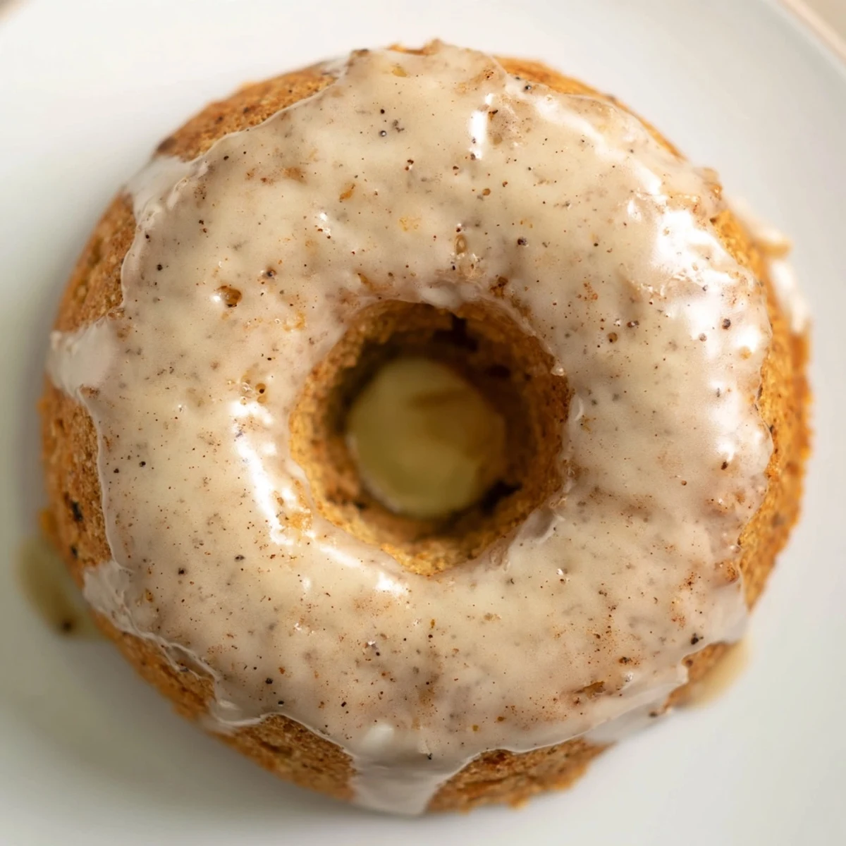 Freshly baked Baked Banana Bread Donuts with a warm, golden-brown glaze drizzled over each moist ring, ready to enjoy.