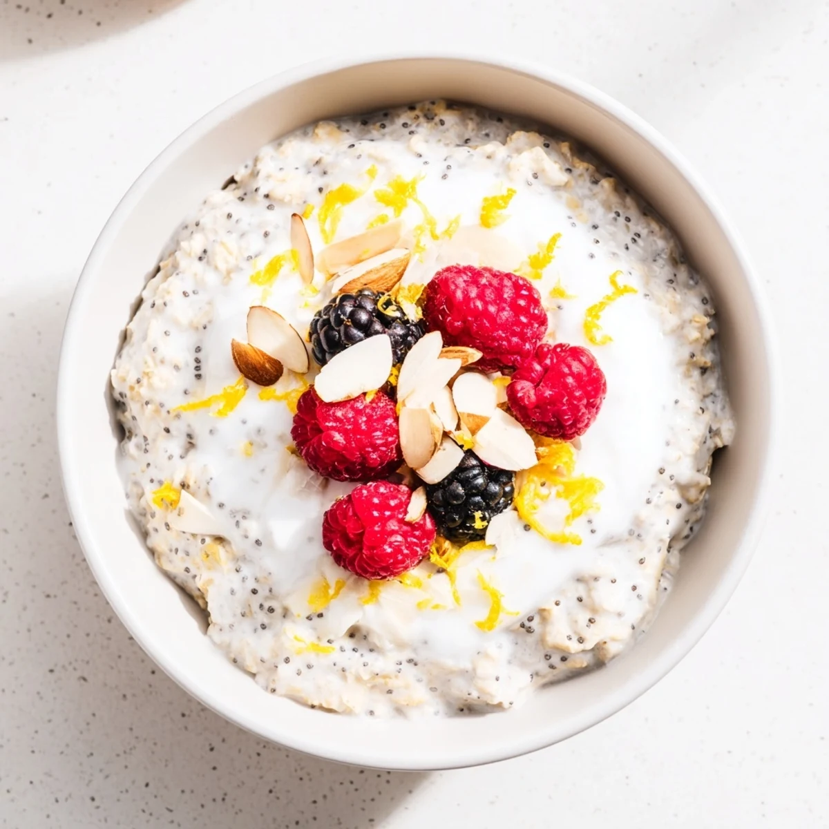 A jar of Vegan Lemon Poppy Seed Overnight Oats topped with fresh berries and sliced almonds.