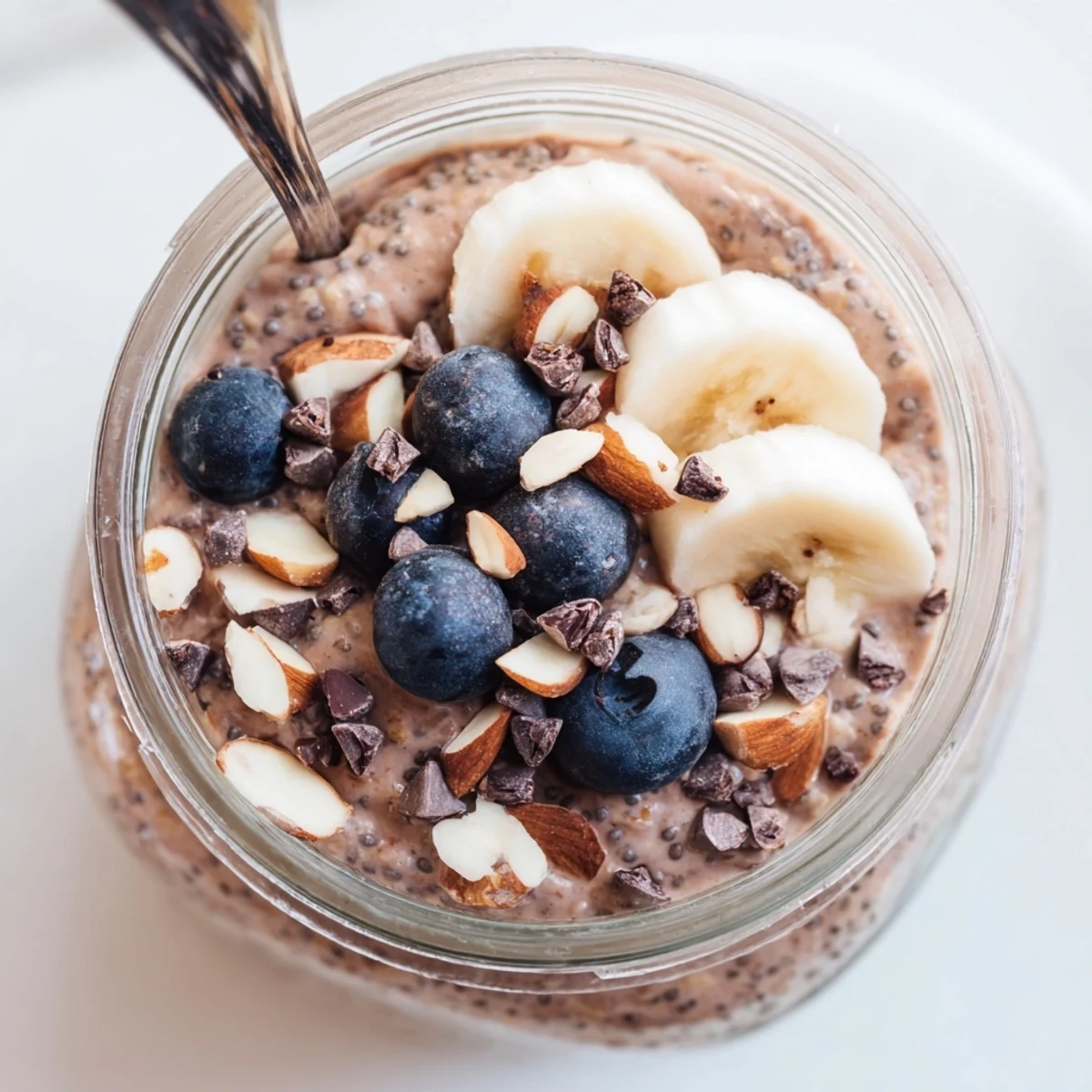 Stirred Ultimate Healthy Chocolate Overnight Oats show a thick, chocolatey texture with chia seeds and mini dark chocolate chips in a glass jar.
