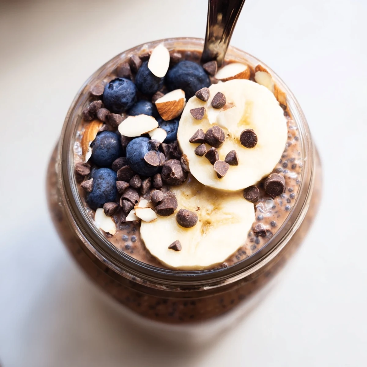 Two servings of Ultimate Healthy Chocolate Overnight Oats topped with fresh berries, nuts, and banana slices, perfect for busy American mornings.