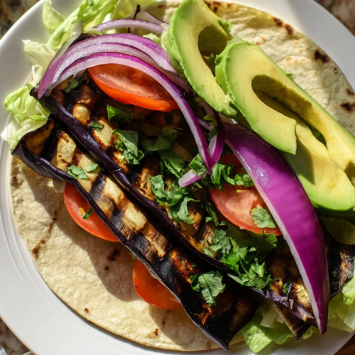 A close view of Charred Eggplant Tacos filled with tomatoes, onions, and cilantro garnish