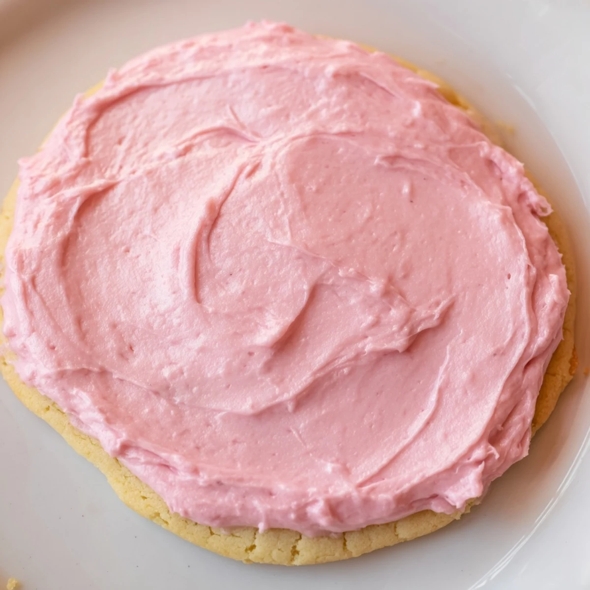 Stack of homemade Crumbl Pink Sugar Cookies on a white plate, ready to serve with milk.