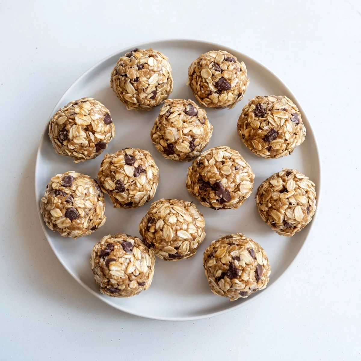 Twelve chilled mint chocolate chip protein balls rest on a marble surface, offering a post-workout treat.