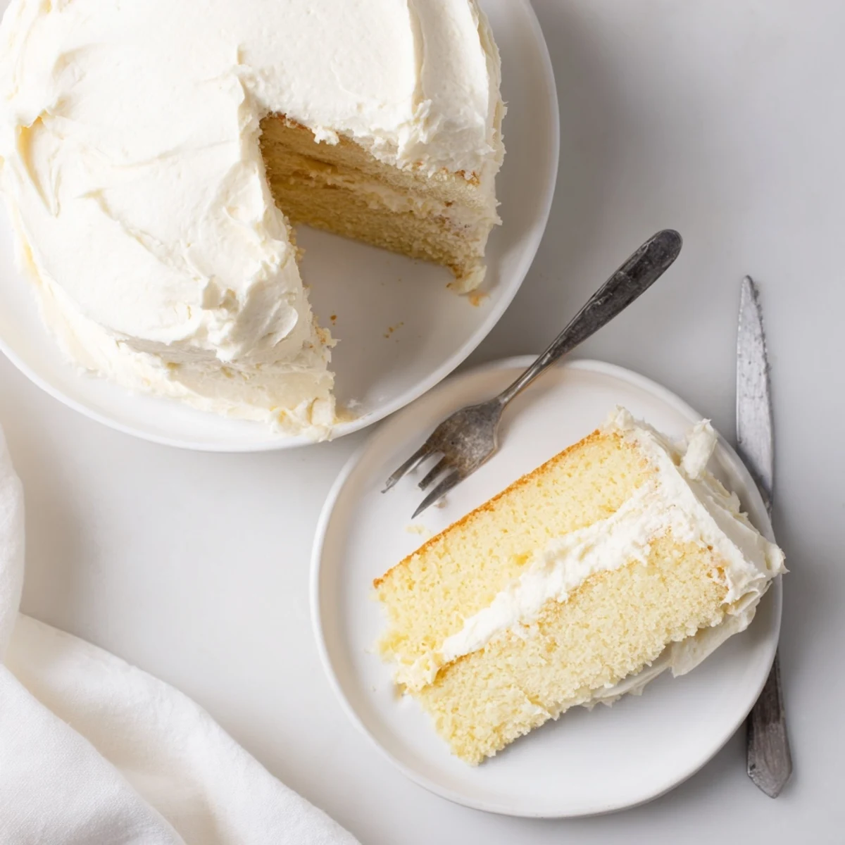 Freshly baked Perfect Vanilla Cake layers with creamy buttercream frosting, presented on a cake stand.