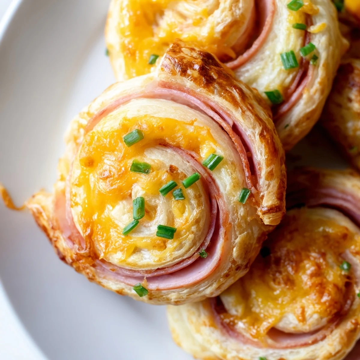 Golden baked Easter Ham Cheddar Pinwheels arranged on a white serving platter