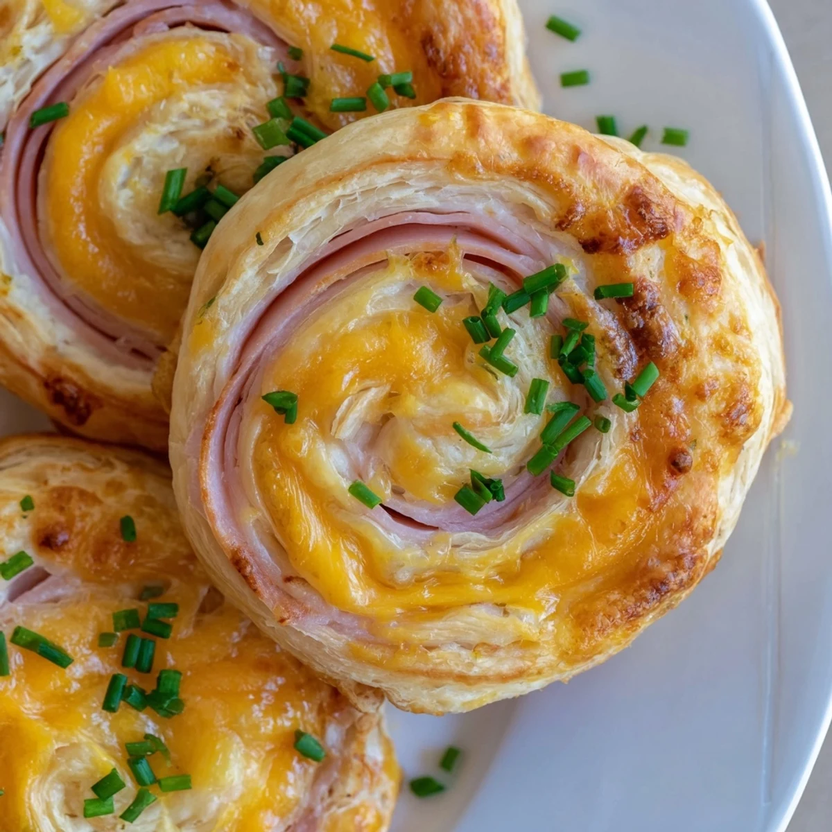 Festive Easter Ham Cheddar Pinwheels topped with fresh herbs ready for spring parties