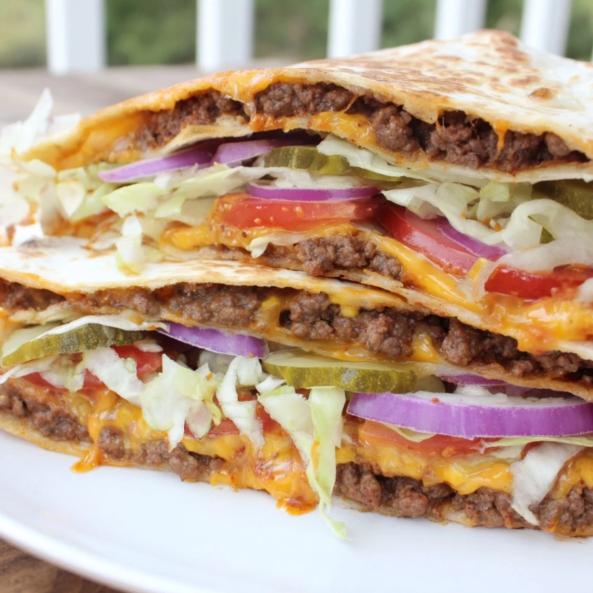 Sliced quesadilla wedges topped with fresh lettuce, tomato, and savory burger sauce