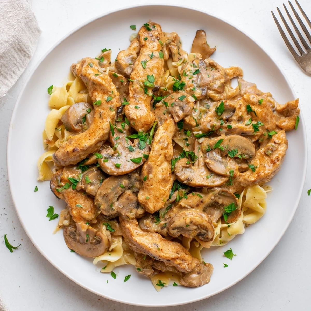 Creamy chicken stroganoff with tender strips and mushrooms in a rich sour cream sauce over egg noodles