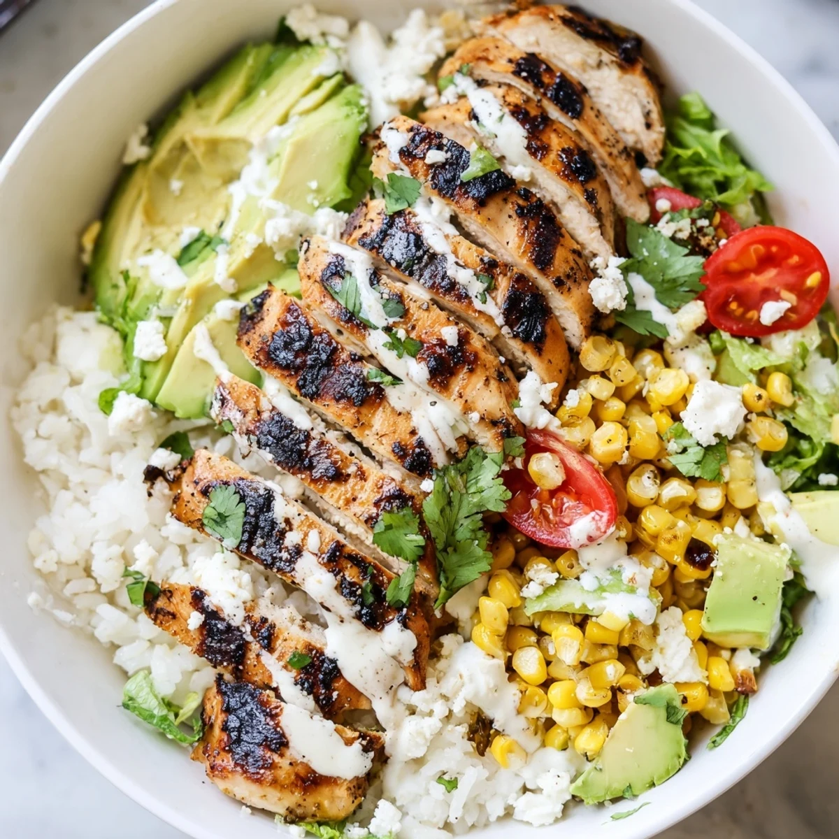 Colorful street corn chicken bowl featuring spiced grilled chicken, roasted corn kernels, crumbled cotija cheese, and zesty lime crema over fluffy rice