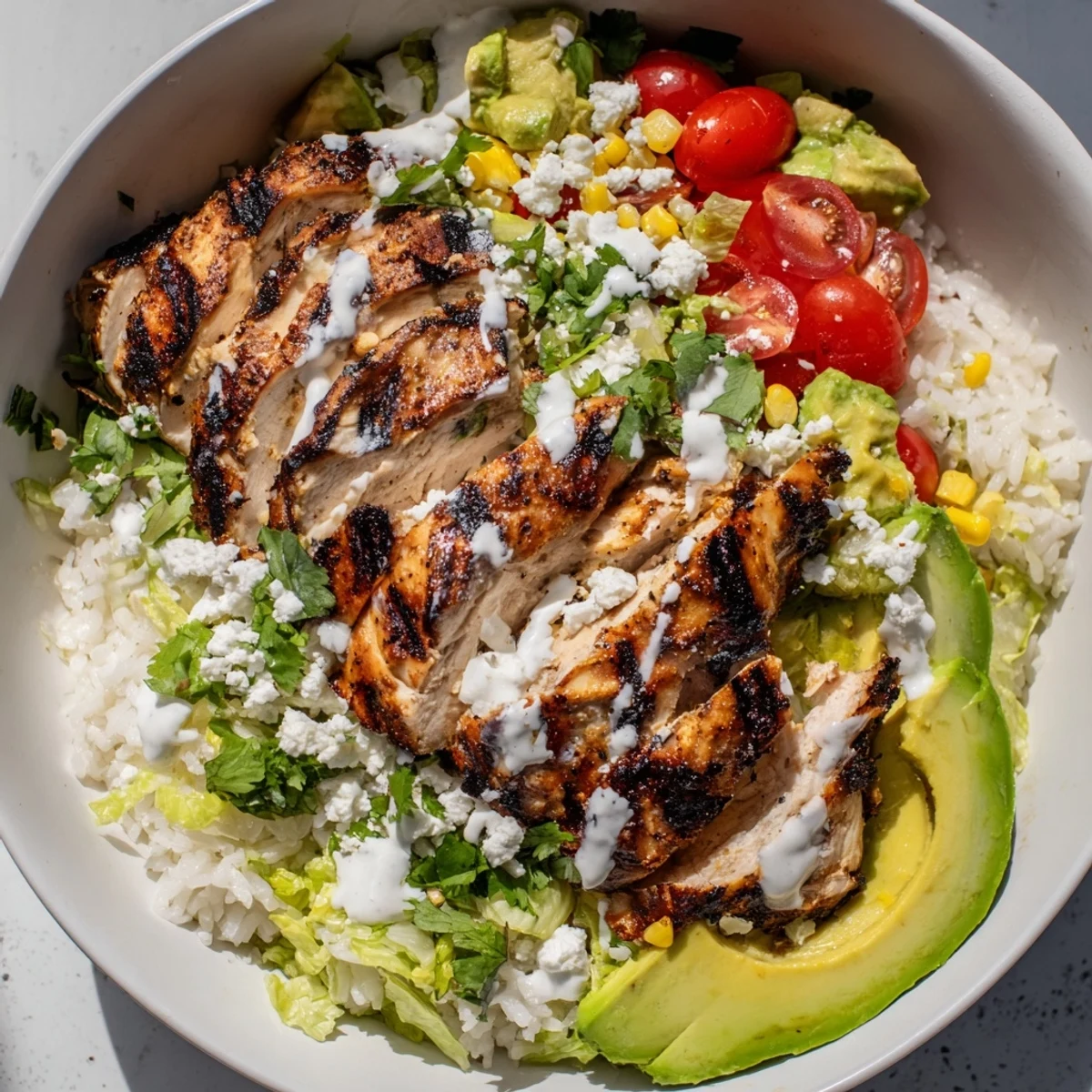 Mexican-inspired tasty street corn chicken bowl with juicy sliced chicken, charred corn, fresh avocado, cherry tomatoes, and creamy lime drizzle