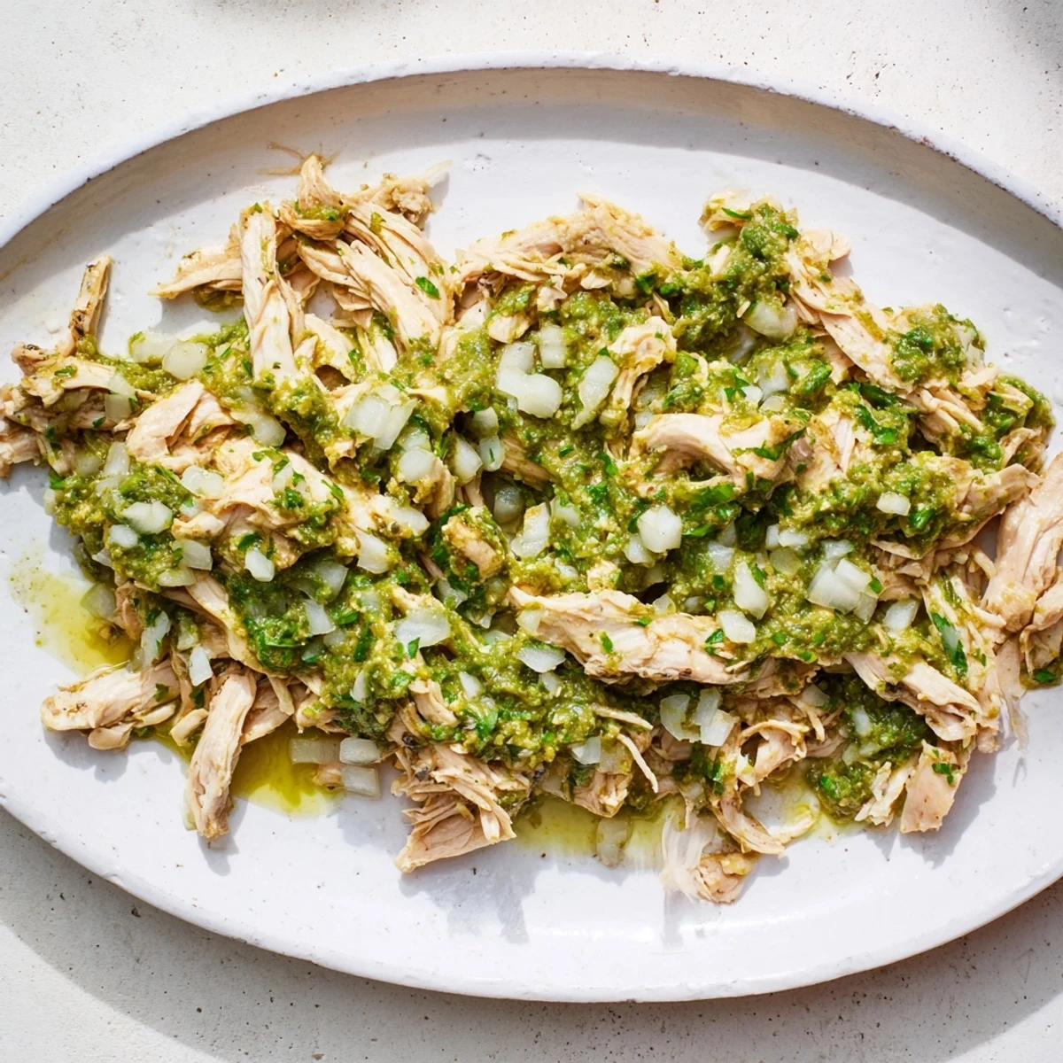 Tangy salsa verde chicken plated with warm corn tortillas fresh cilantro and creamy avocado slices