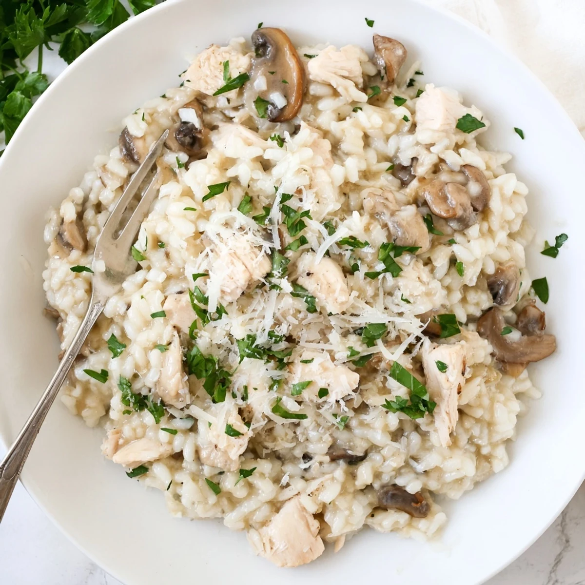 Golden chicken and mushroom baked risotto sprinkled with fresh parsley and grated Parmesan