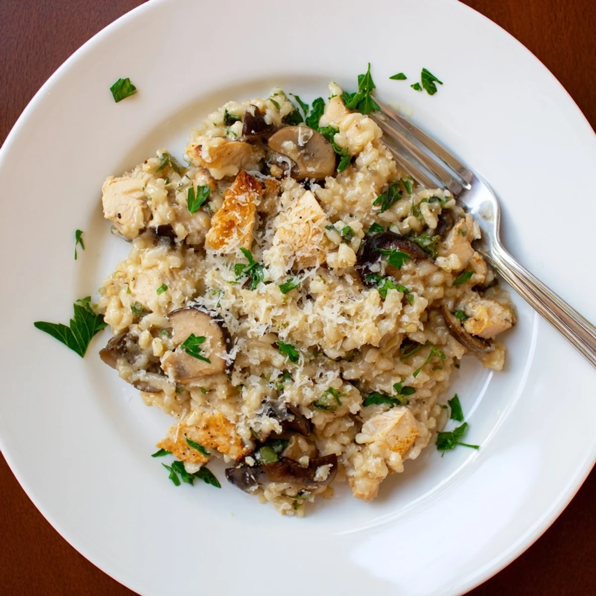 Steaming chicken and mushroom baked risotto in a white bowl garnished with green parsley