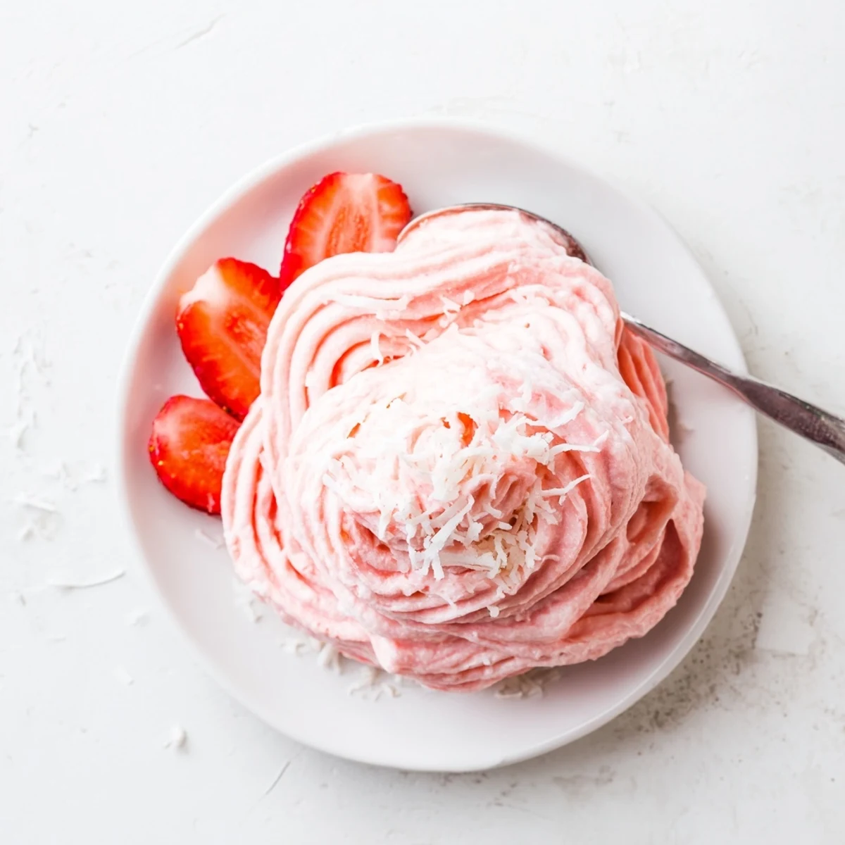 Creamy pink Frozen Strawberry Dole Whip Delight swirled into a glass bowl with fresh strawberry garnish