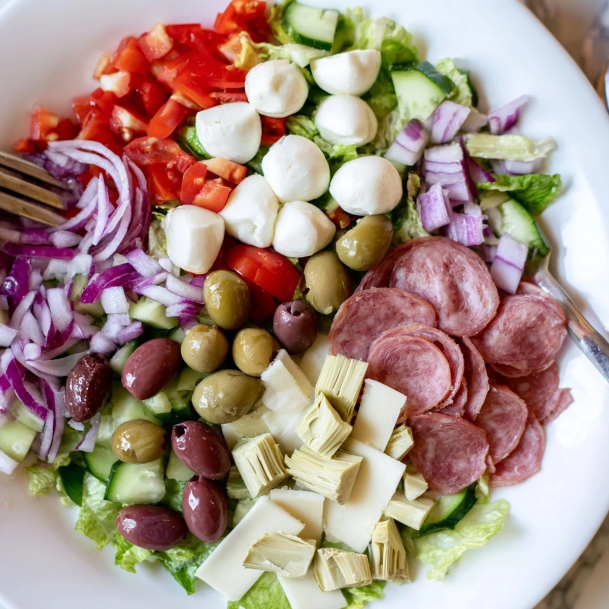 Vibrant Italian Antipasti Chopped Salad featuring romaine, mozzarella, olives, and cured meats tossed in tangy herb dressing