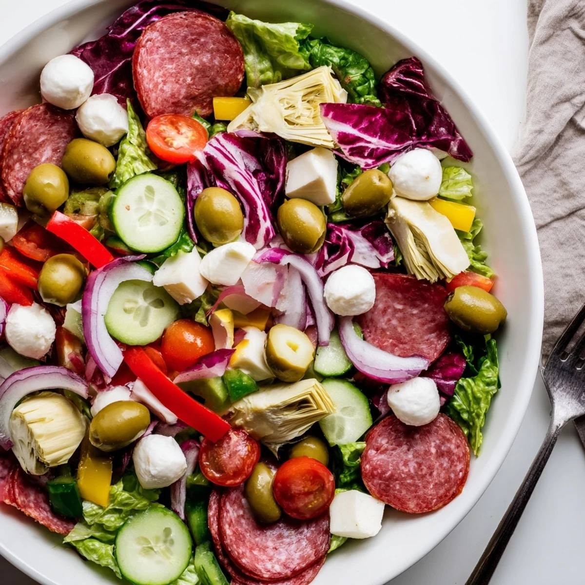 Colorful Antipasti Chopped Salad bowl with fresh vegetables and Italian ingredients arranged on a white serving plate