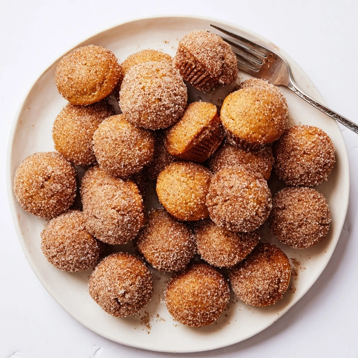 Close-up of warm cinnamon sugar mini muffins piled high on a wooden cutting board ready for breakfast