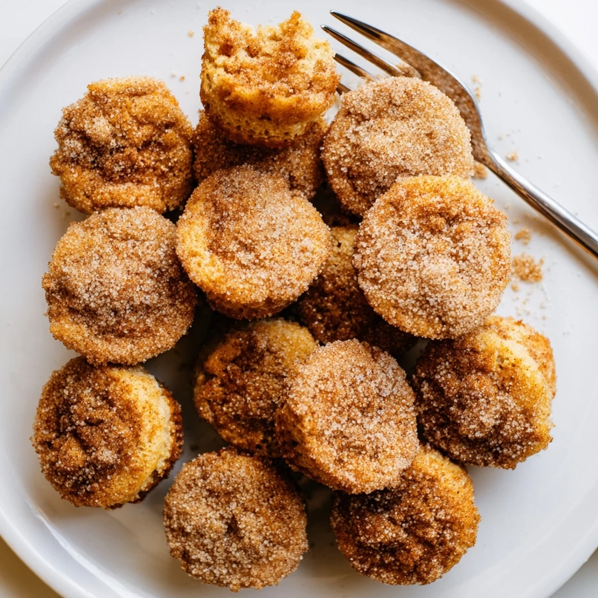 Batch of tender bite-sized cinnamon sugar mini muffins fresh from the oven with glistening buttered tops