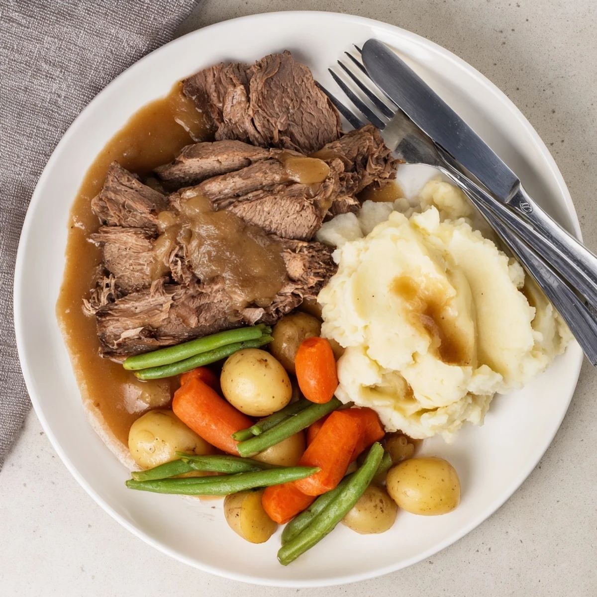 Slow-cooked Southern style pot roast drizzled with rich gravy alongside fluffy mashed potatoes
