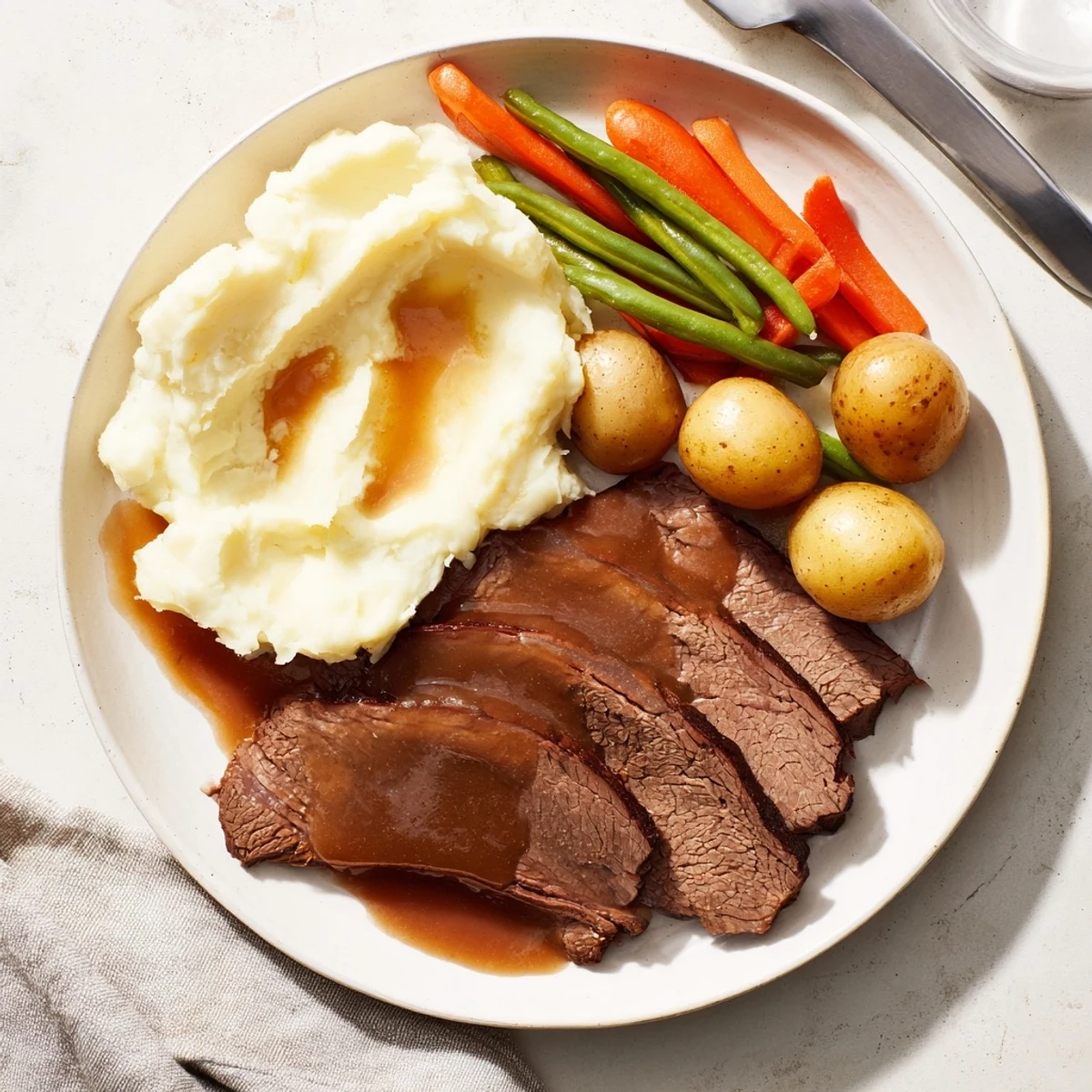 Fork-tender Southern style pot roast served with vegetables mashed potatoes and seasoned green beans