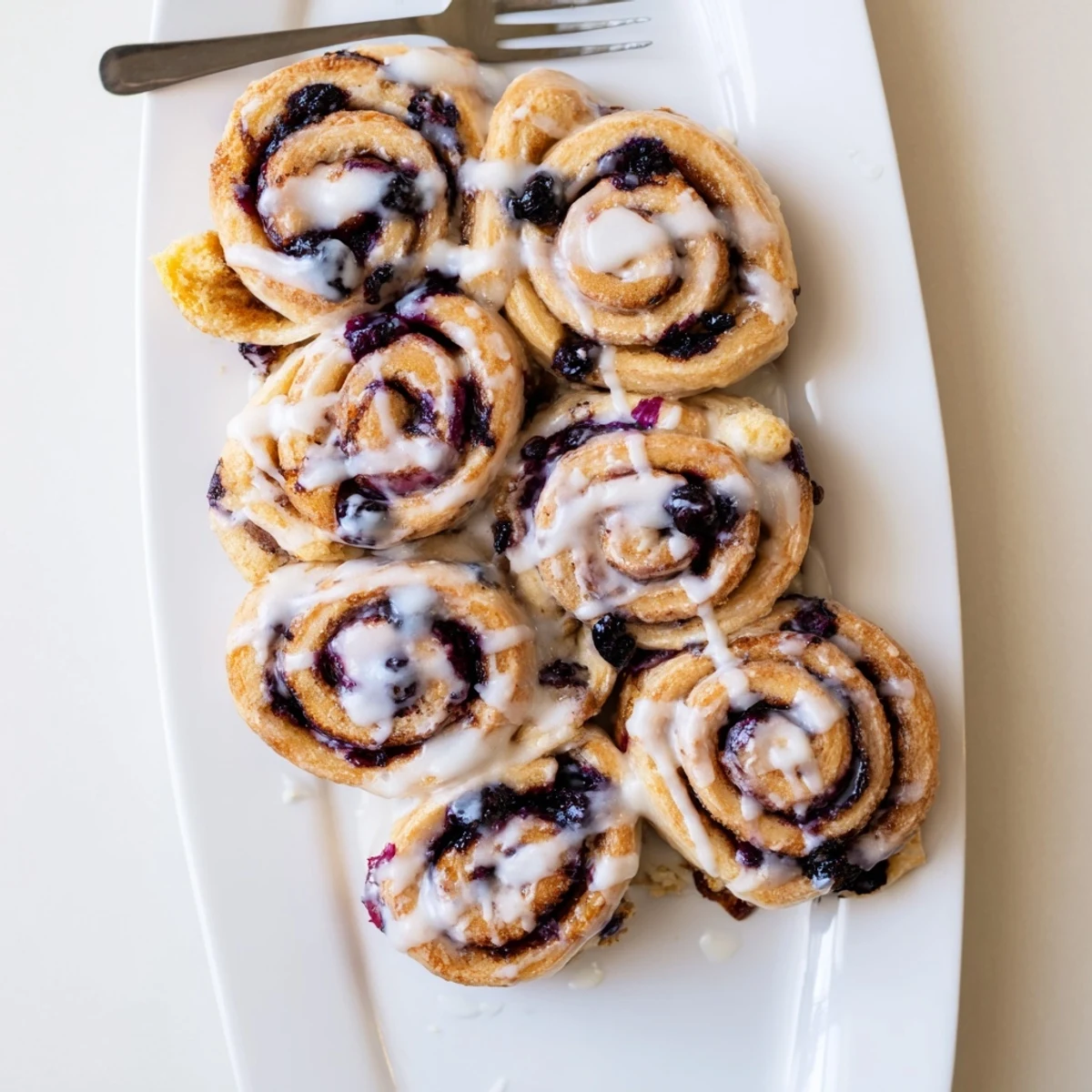 Golden Lemon Blueberry Rolls drizzled with zesty glaze on a rustic wooden board