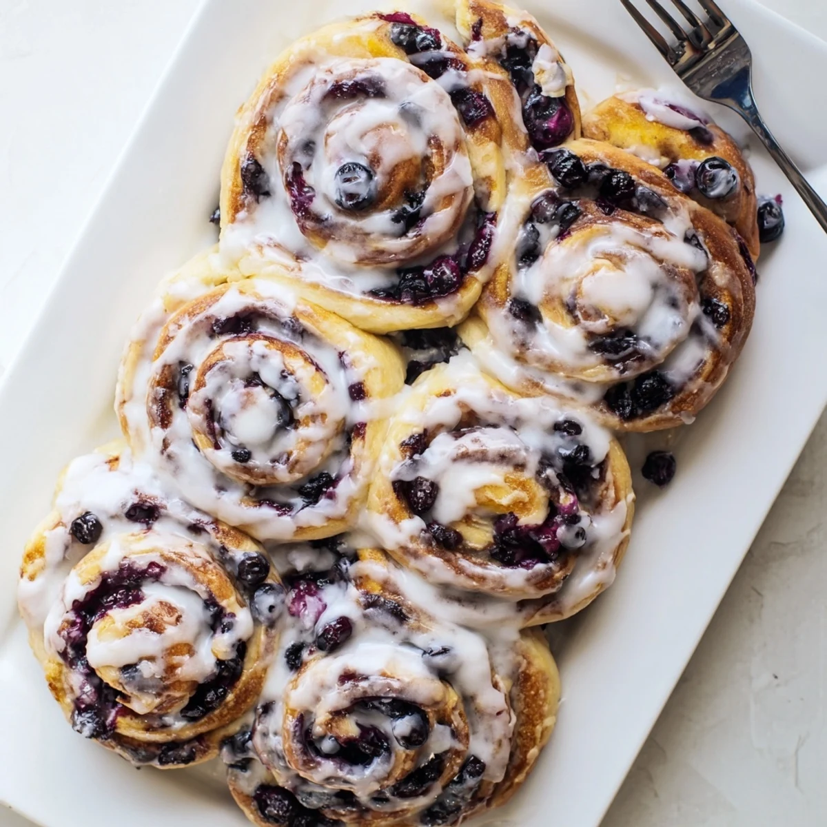 Soft swirled pastry revealing purple blueberry filling and bright lemon zest inside
