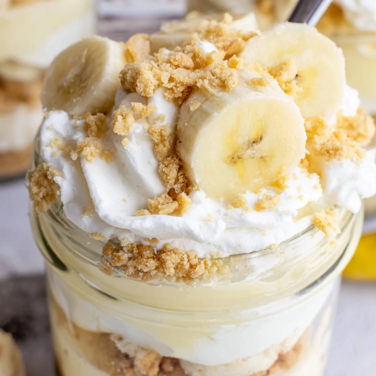 Creamy no bake banana pudding cheesecake cups layered with vanilla wafer crumbs and fresh banana slices