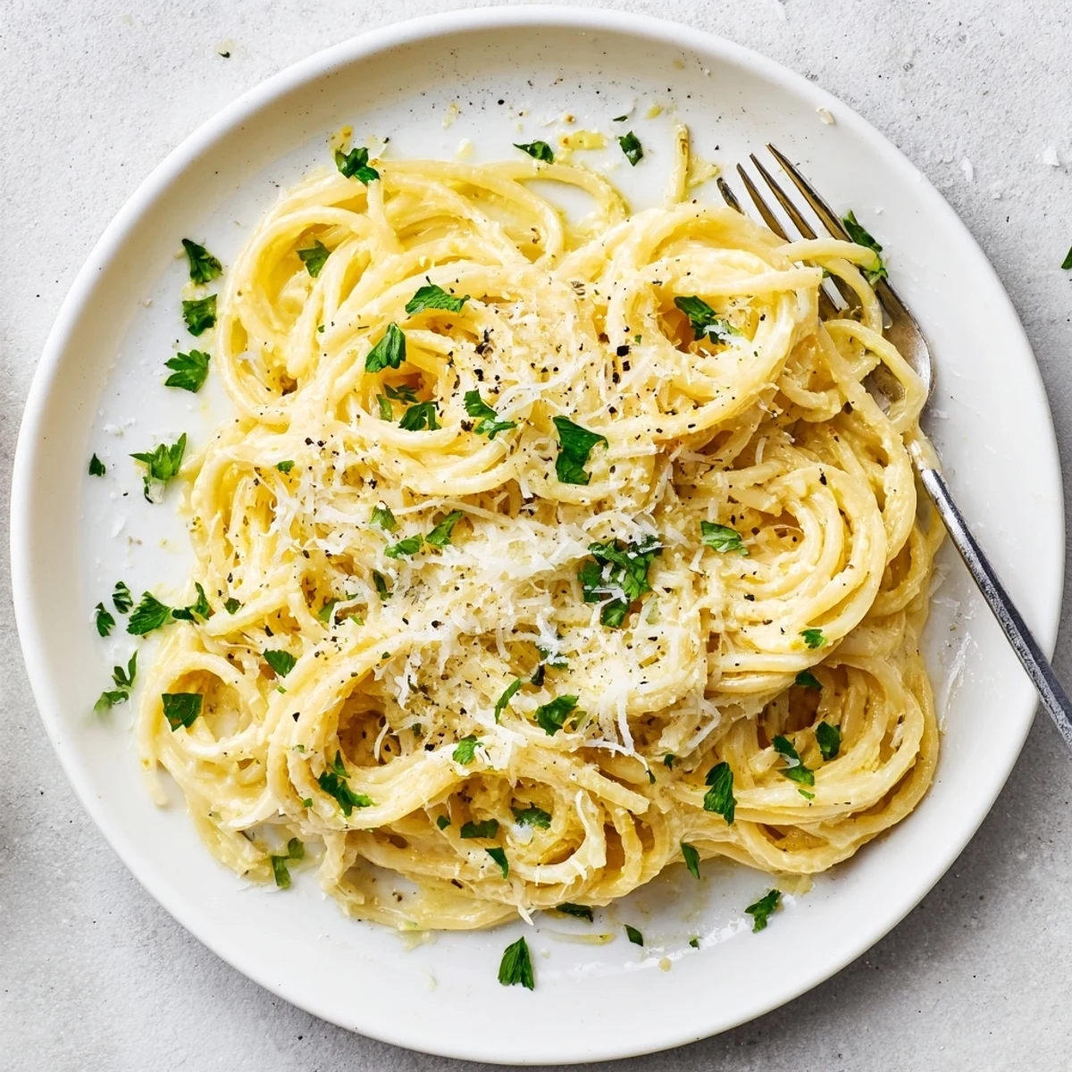 Golden spaghetti coated in zesty Parmesan lemon sauce with fresh parsley garnish