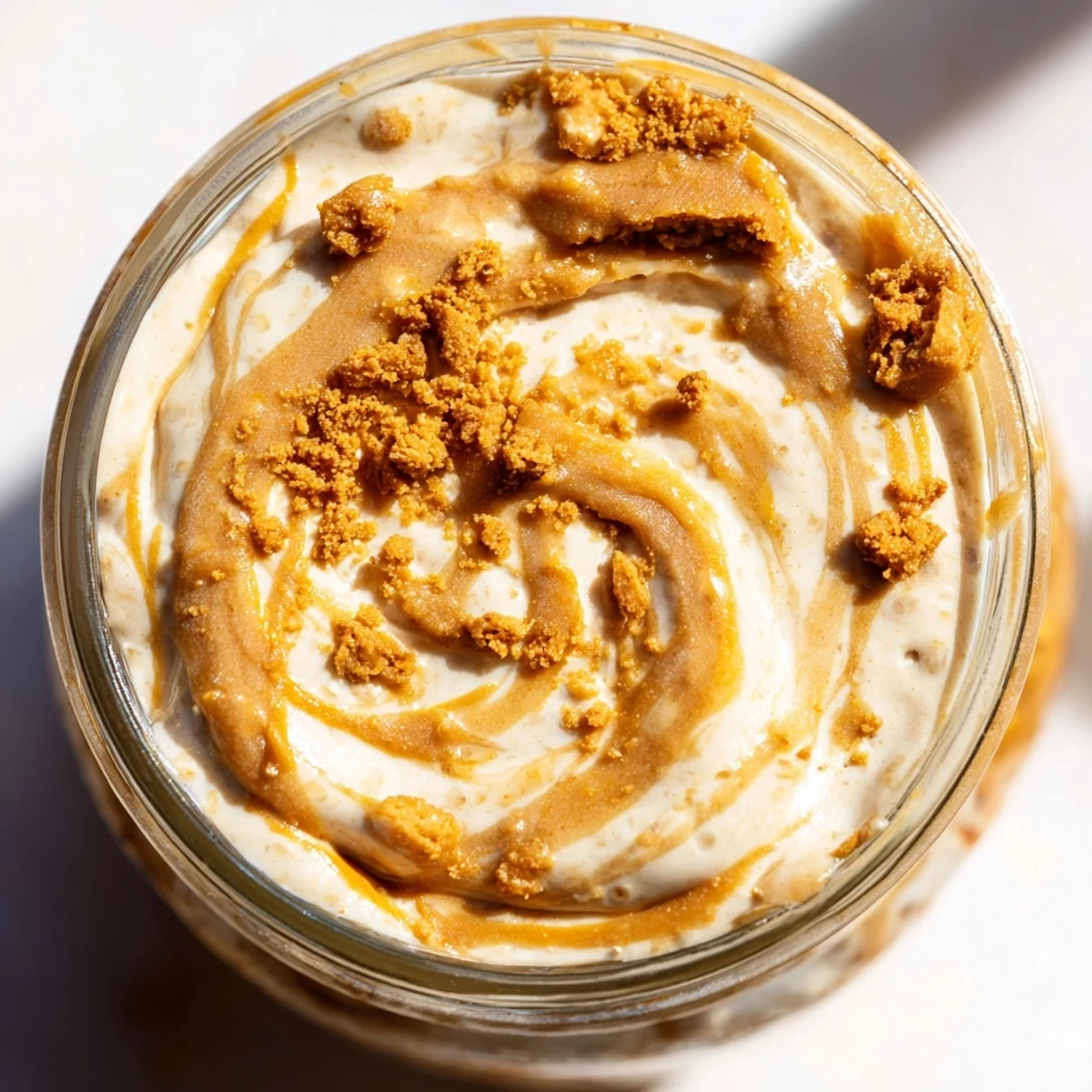 Creamy Quick Biscoff Overnight Oats served in a jar with crushed cookie topping and caramel drizzle