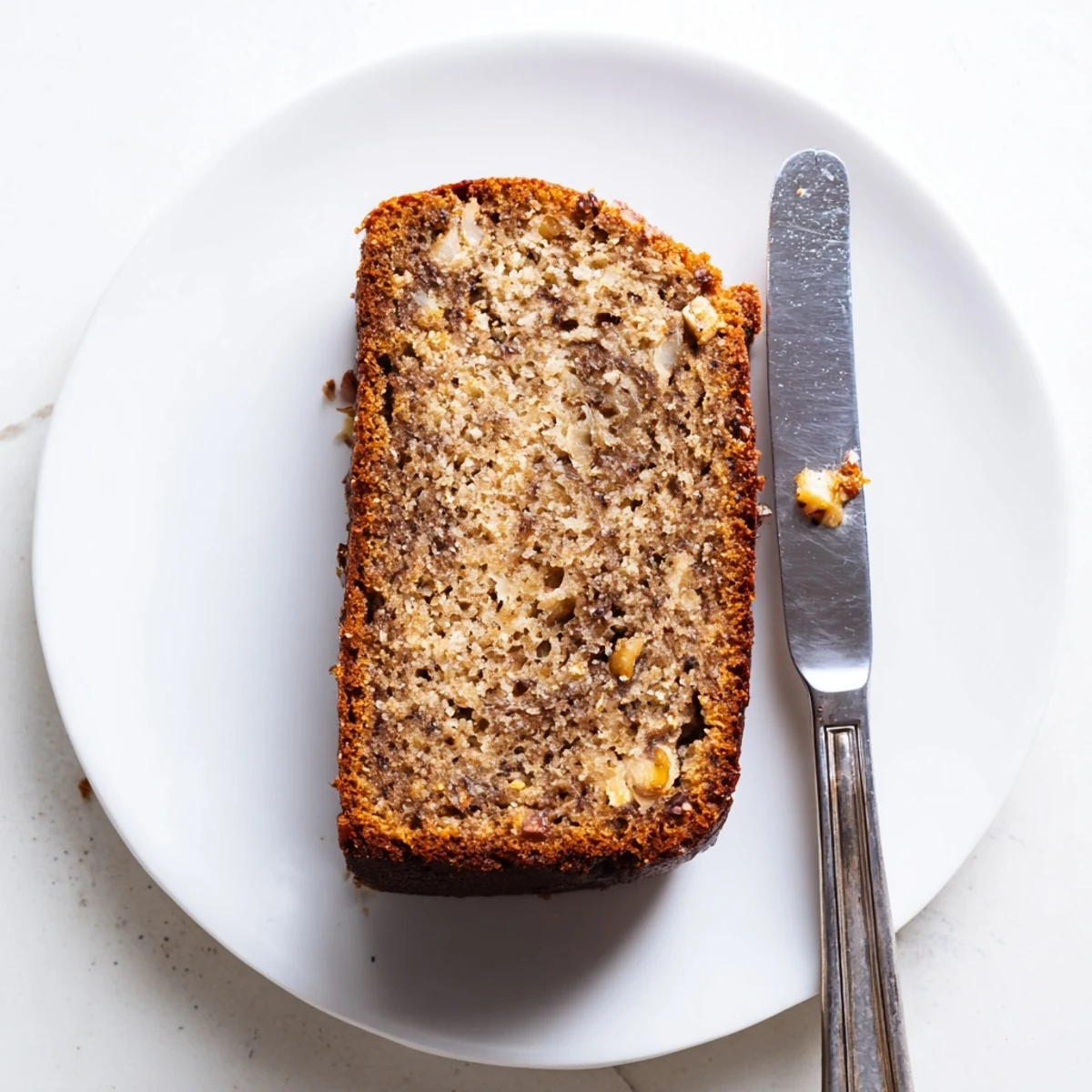Thick cut of super moist banana bread served alongside ripe bananas and melting butter