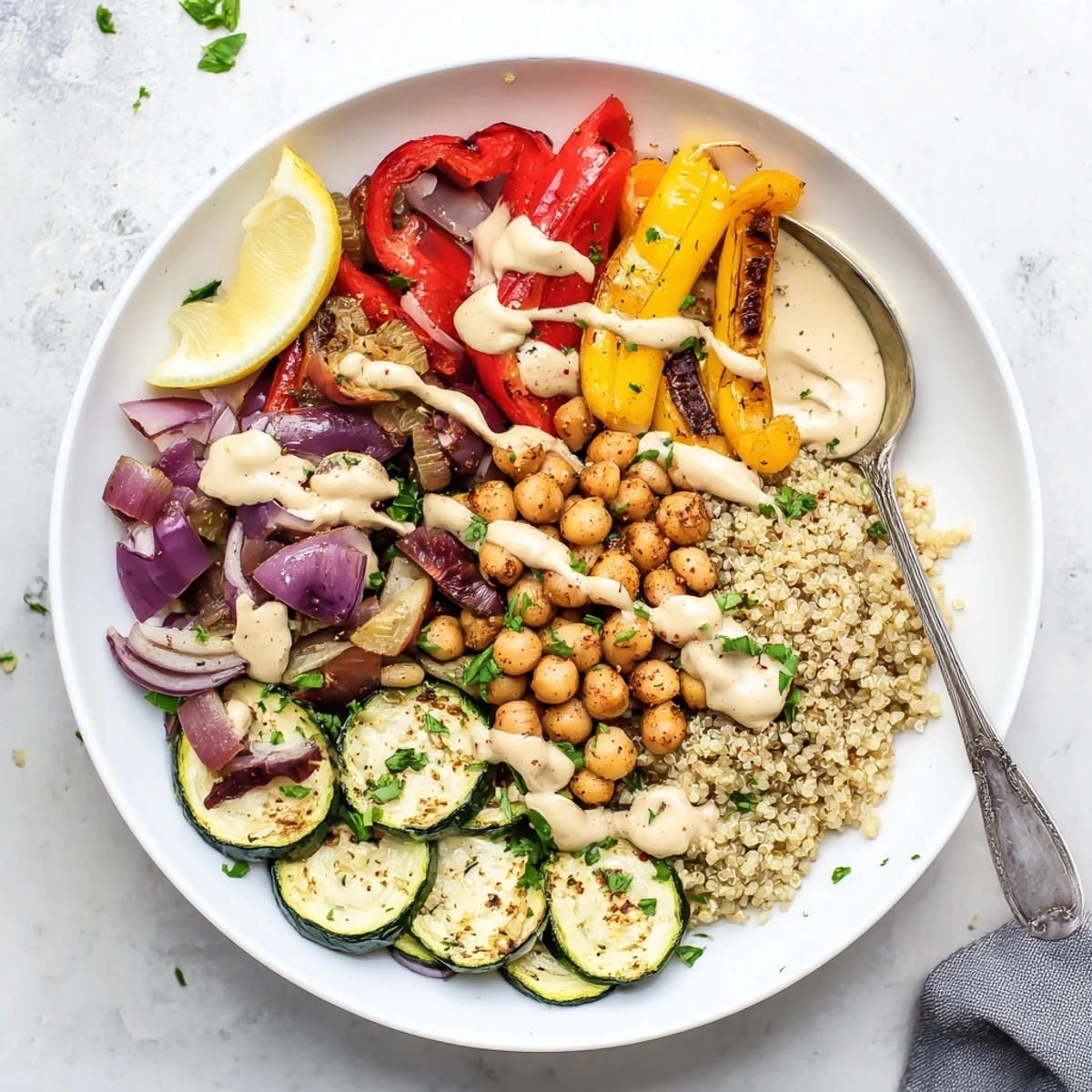 Warm vegan Mediterranean roasted vegetables bowl served over quinoa and topped with fresh parsley and kalamata olives.