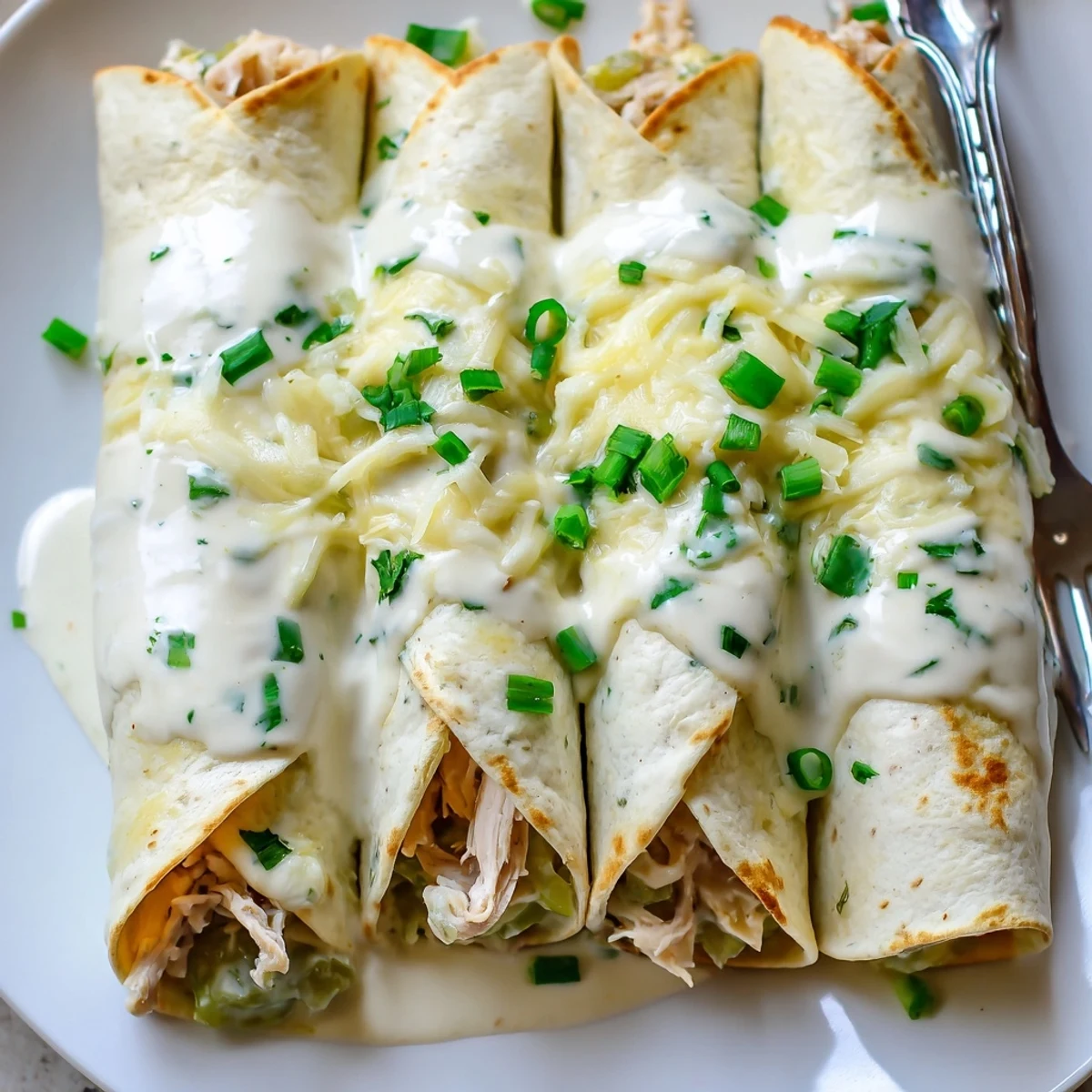 White Rotisserie Chicken Enchiladas bubbling with creamy sauce, melted cheese topping