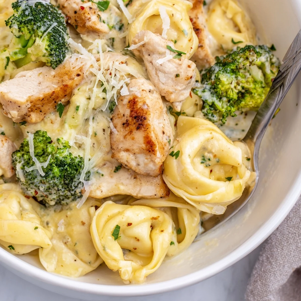 Weeknight Creamy Garlic Parmesan Tortellini Chicken Broccoli Recipe tossed in silky sauce, garnished parsley