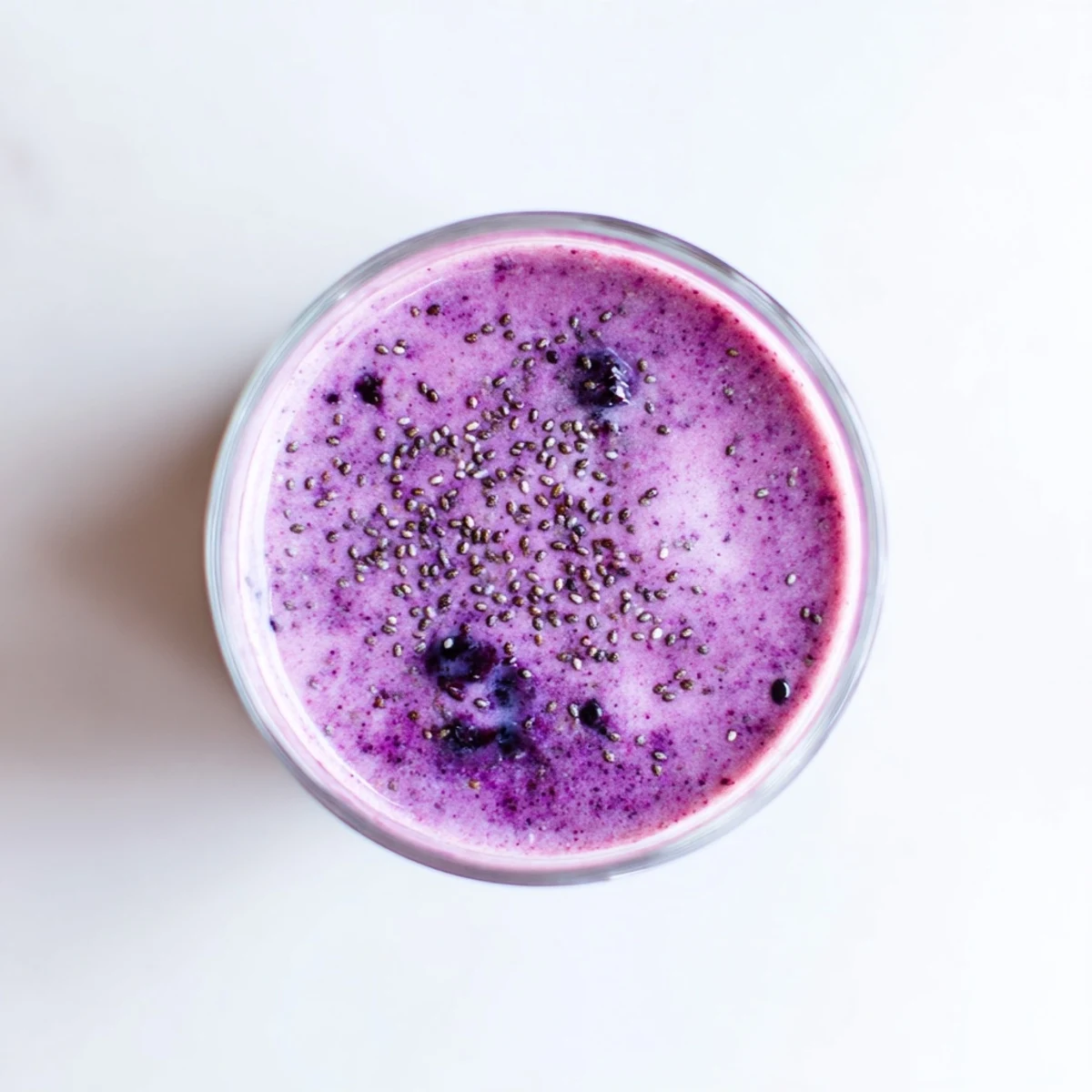 Creamy chia seed smoothie blended with mixed berries and banana in clear serving glass