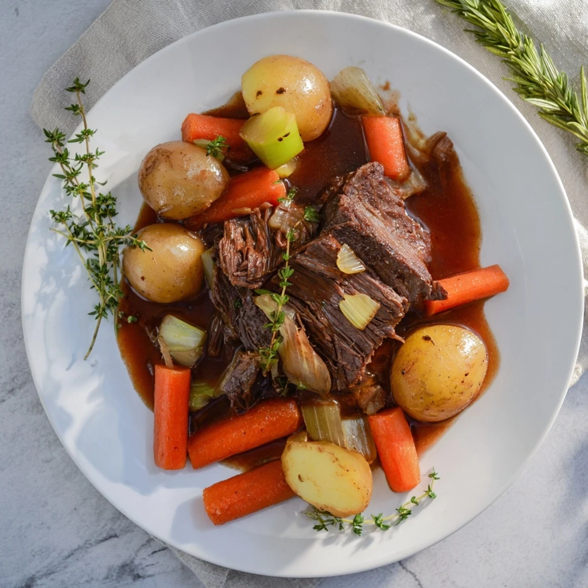 Golden herb braised beef chuck roast with tender carrots and onions in rich sauce