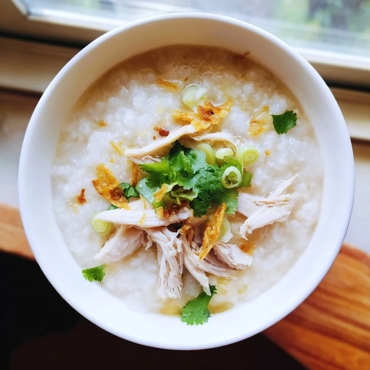Steaming bowl of savory chicken congee with tender shredded chicken and sliced century eggs